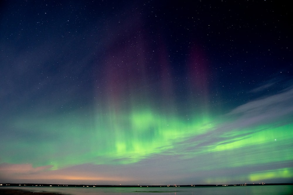 a green and purple aurora over a body of water