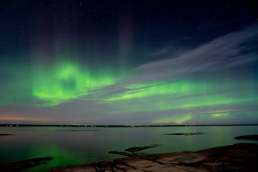 a green and purple aurora bore over a body of water