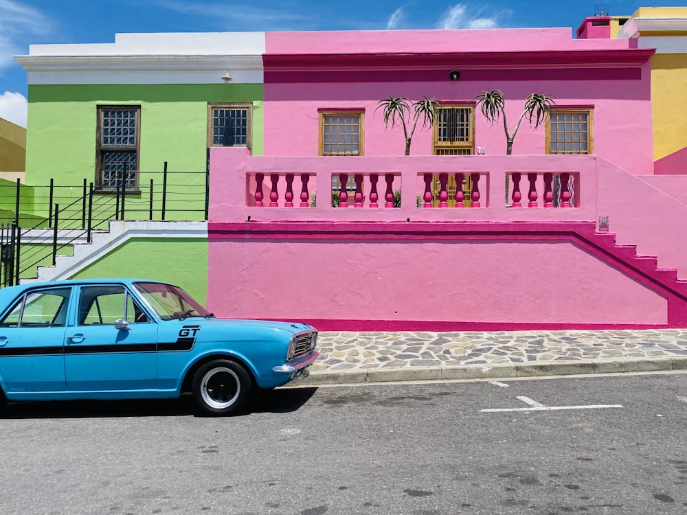 a blue car parked in front of a multi - colored building