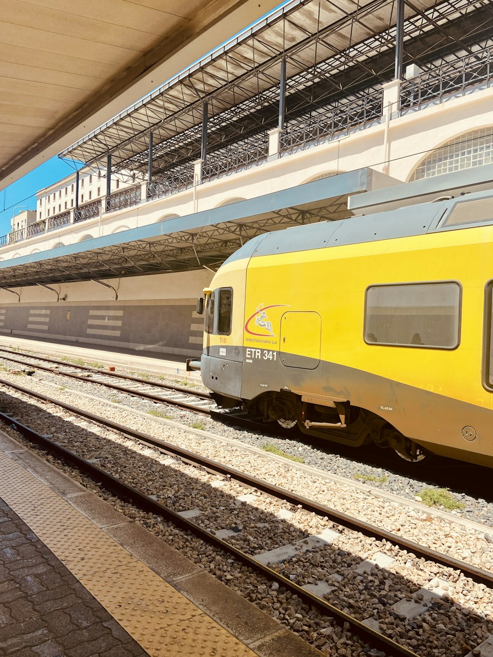 Un treno giallo che viaggia lungo i binari del treno vicino a una stazione ferroviaria