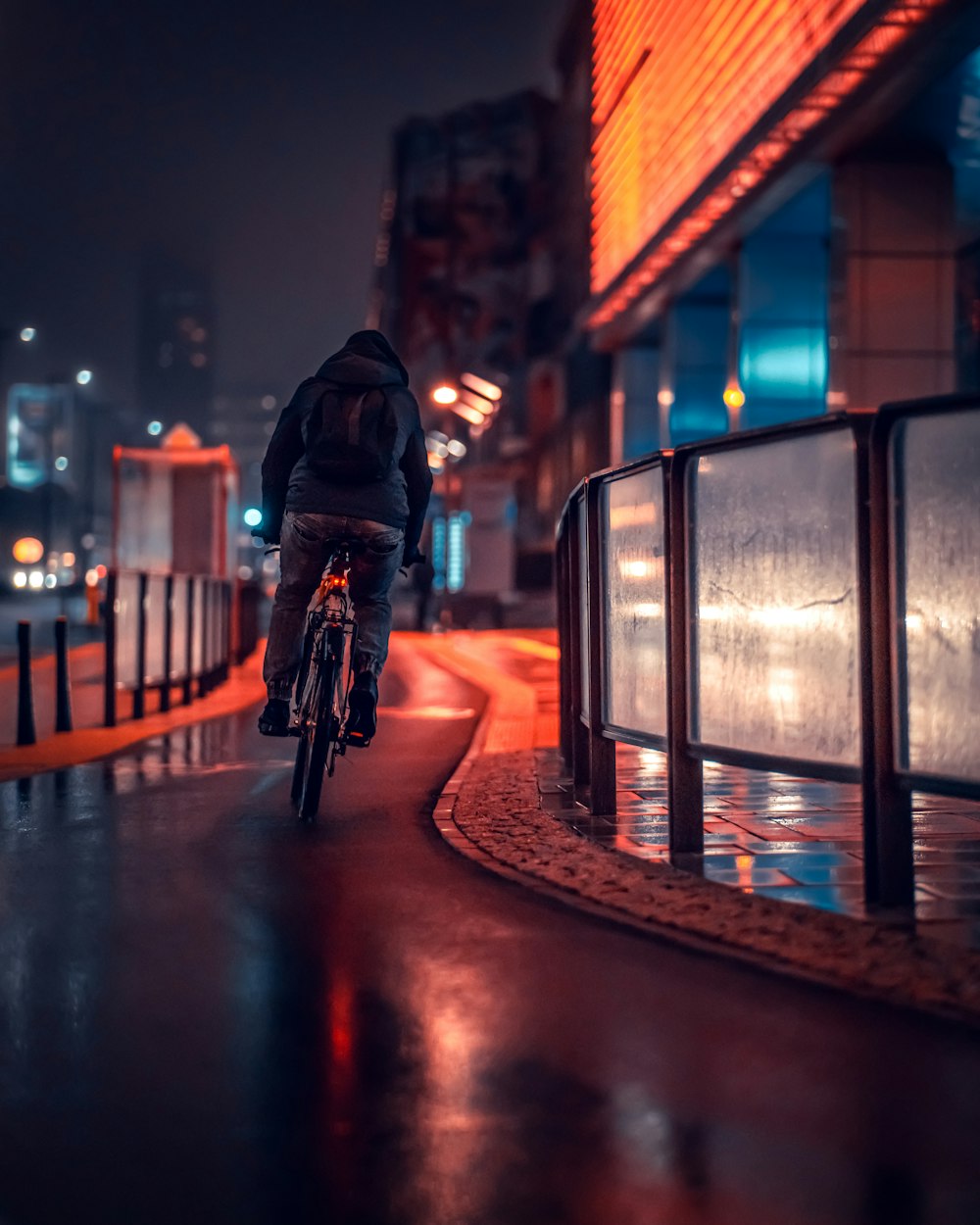 a man riding a bike down a rain soaked street