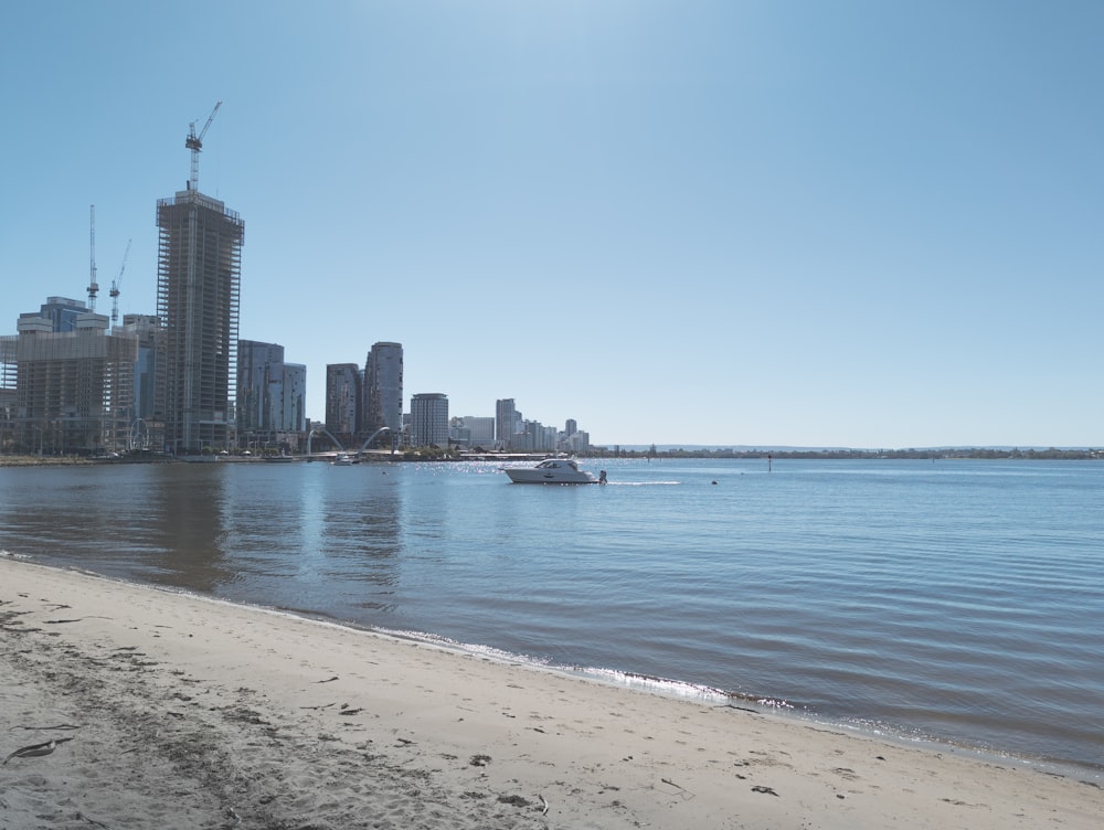 Una playa con un barco en el agua y una ciudad al fondo