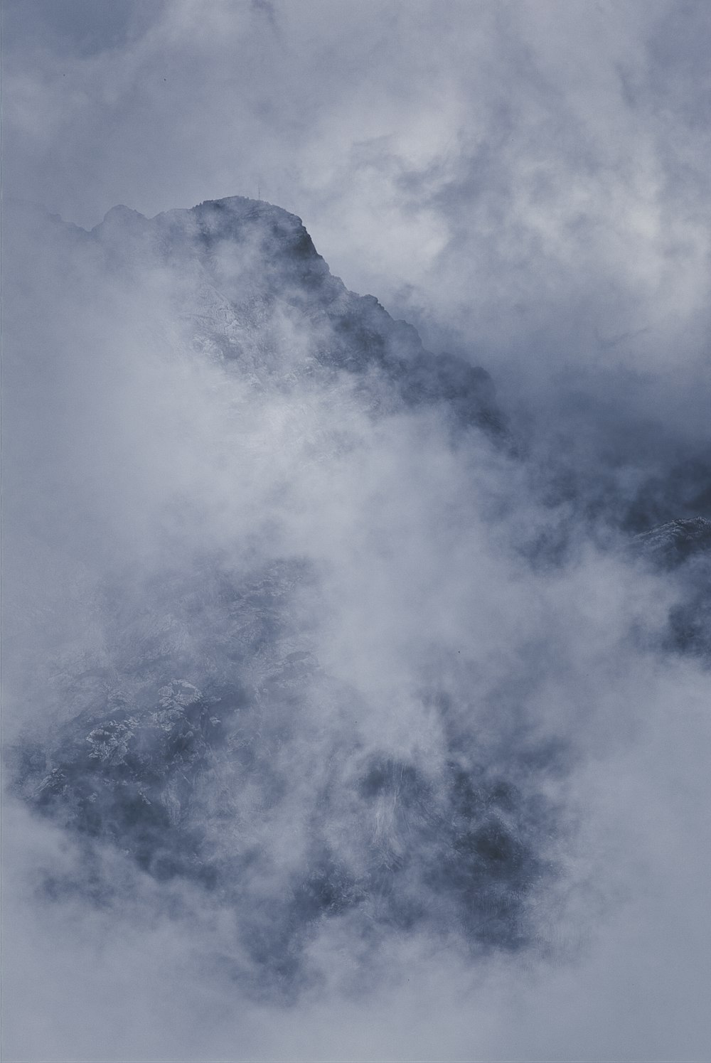 a large mountain covered in clouds in the sky