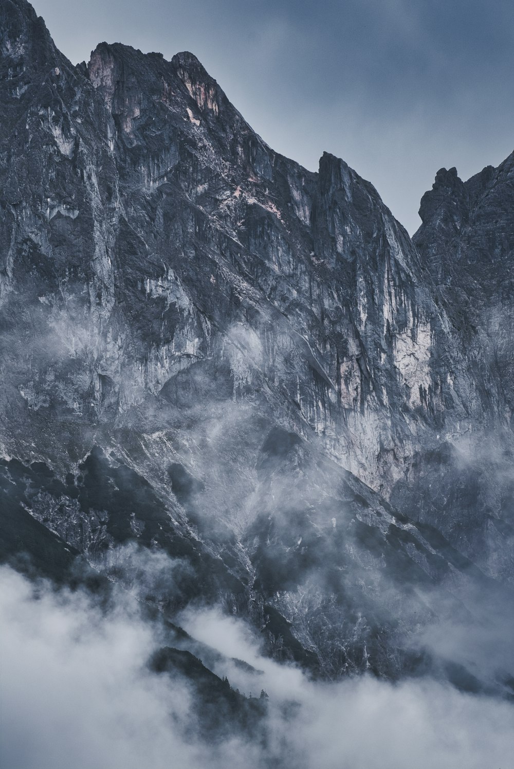 a mountain covered in fog and clouds under a cloudy sky