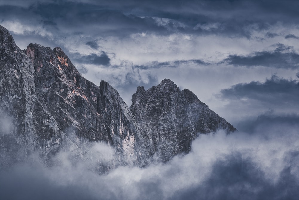 a very tall mountain covered in clouds under a cloudy sky