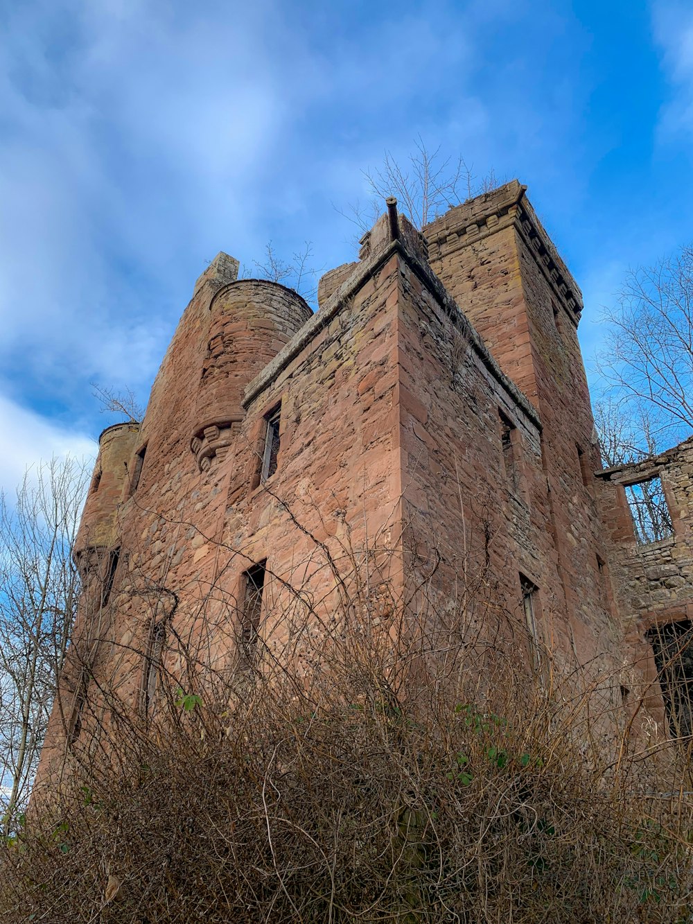 a tall brick building sitting next to a forest