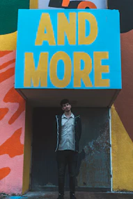 a man standing in front of a sign that says and more