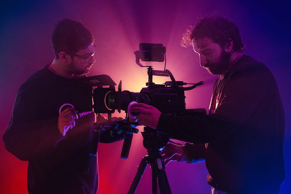 a couple of men standing next to a camera