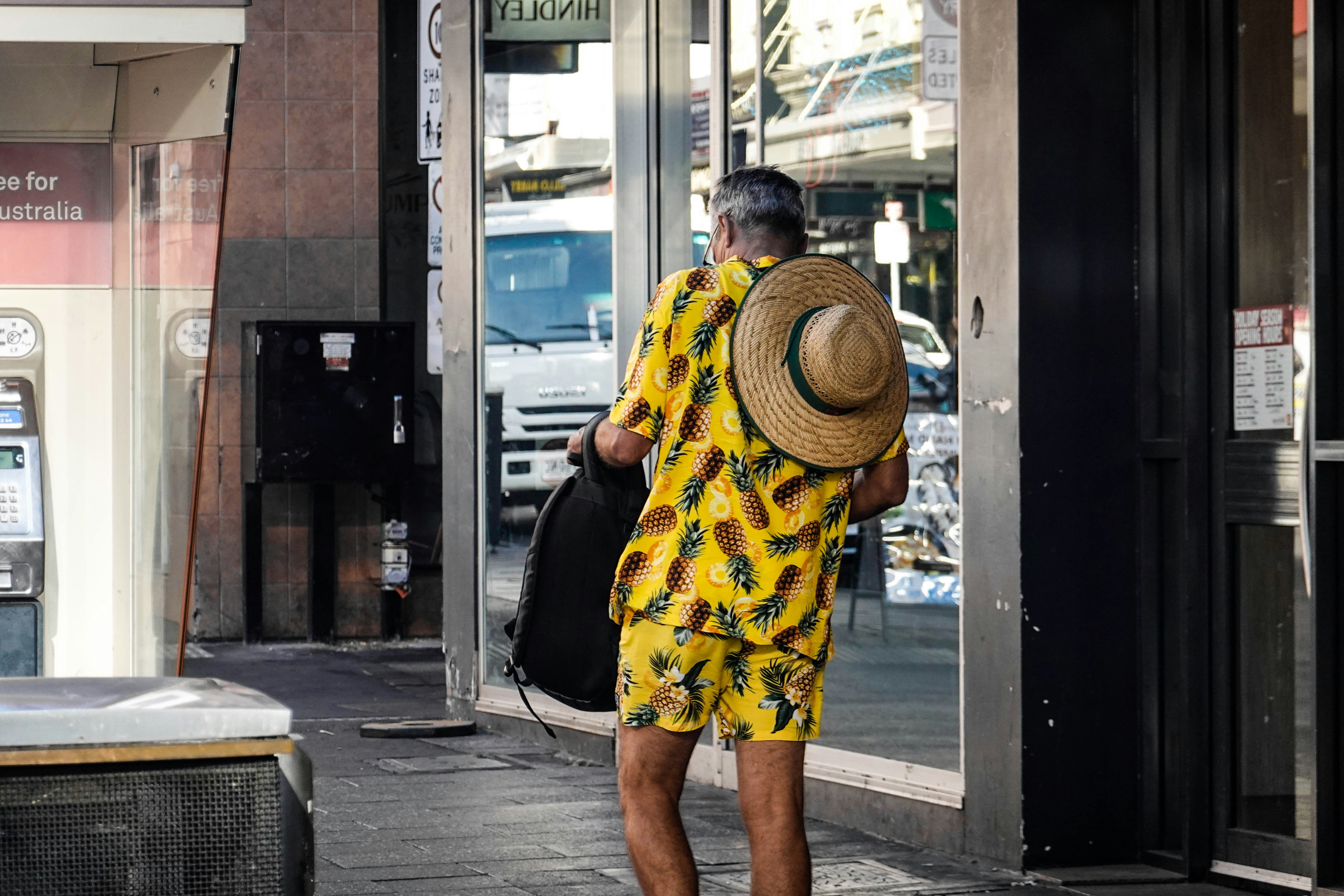 a man with a straw hat walking down a sidewalk