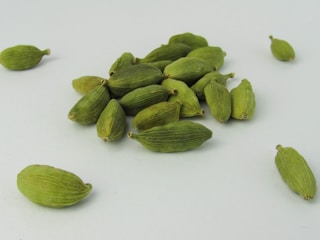 a pile of green cardamoas sitting on top of a white table