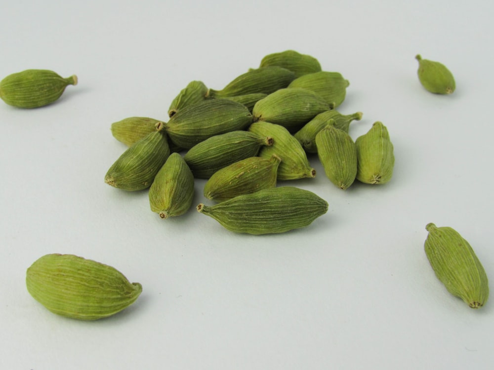 a pile of green cardamoas sitting on top of a white table