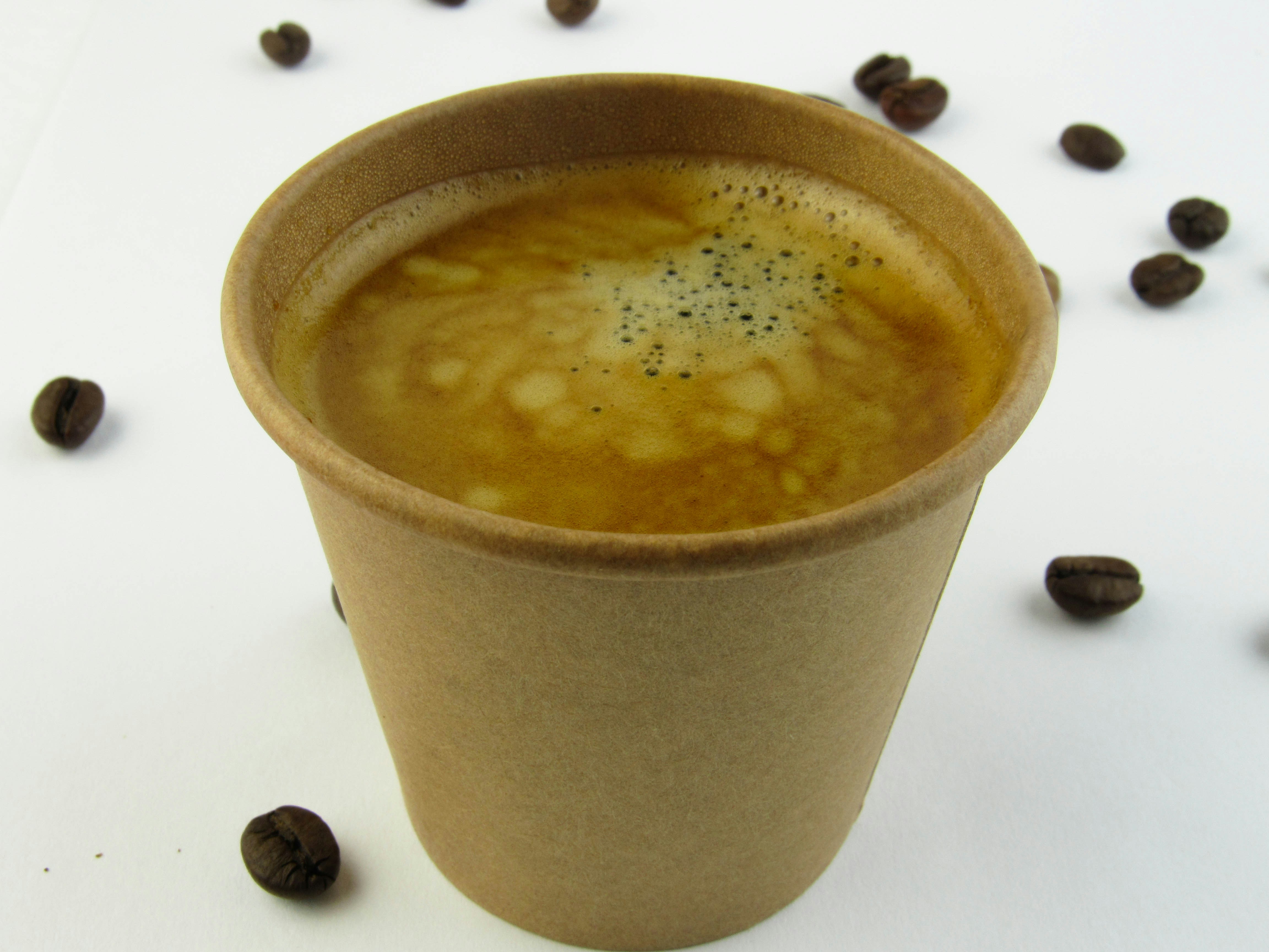 Coffee in a paper cup with beans