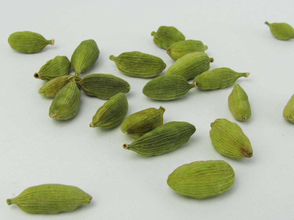 uma pilha de sementes de cardamoa verde em uma superfície branca