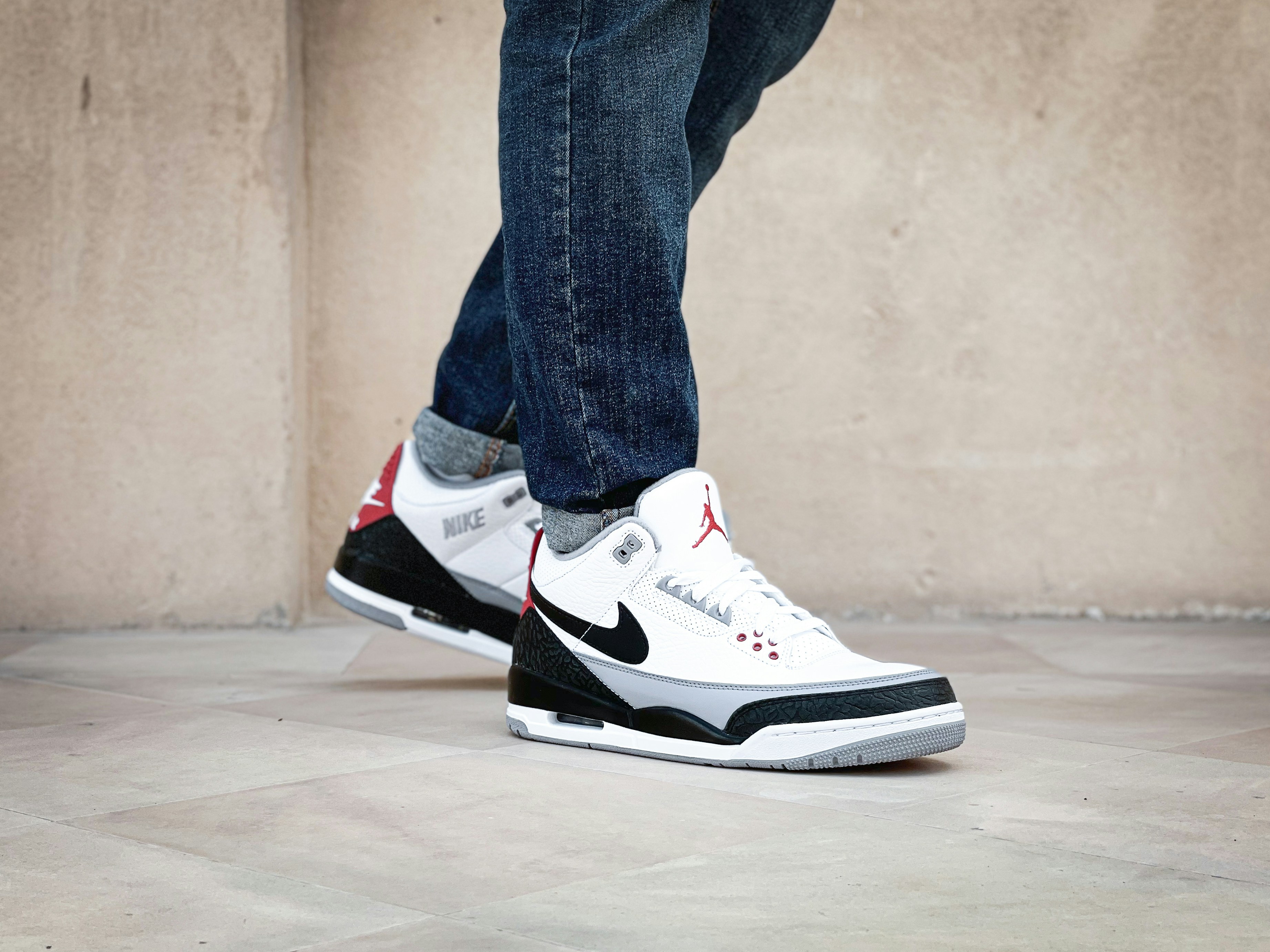 a person standing on a tiled floor with a pair of sneakers