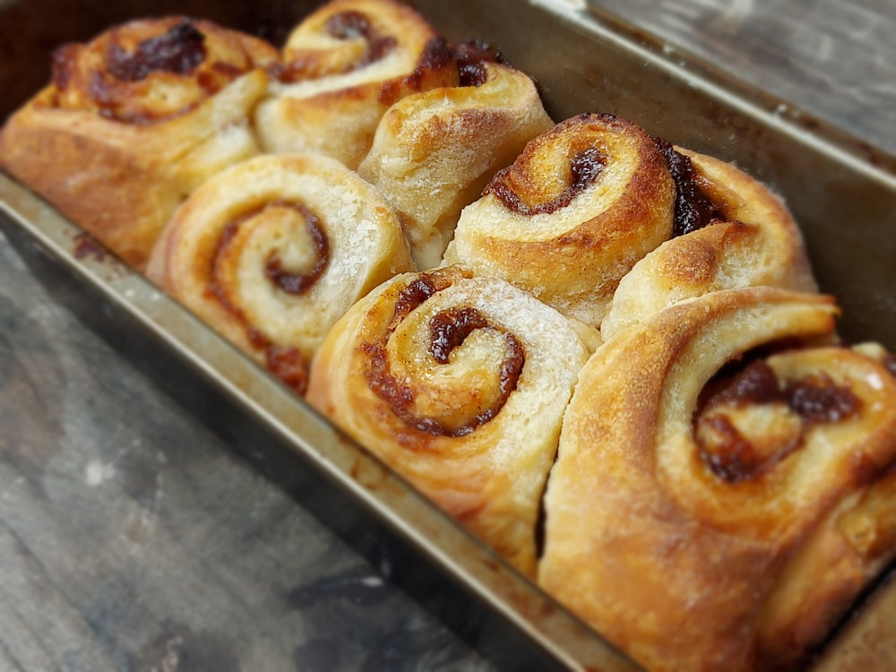 a pan filled with cinnamon rolls on top of a wooden table