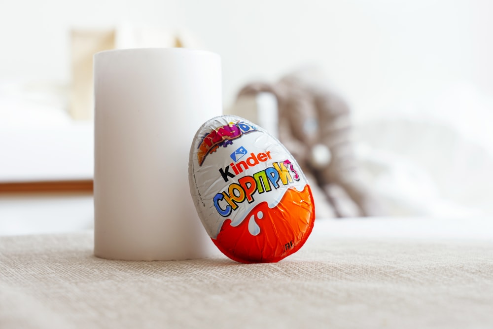 a white cup sitting next to an orange and white egg