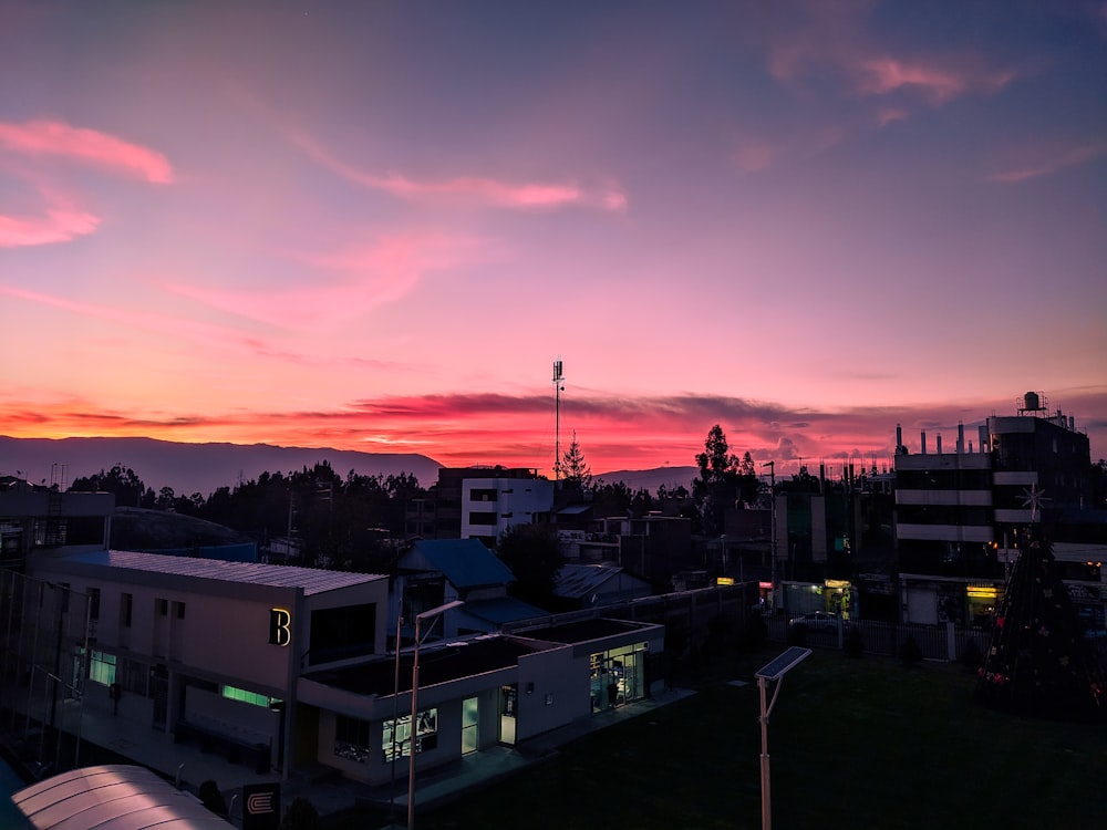 uma vista do pôr do sol de uma cidade com edifícios em primeiro plano