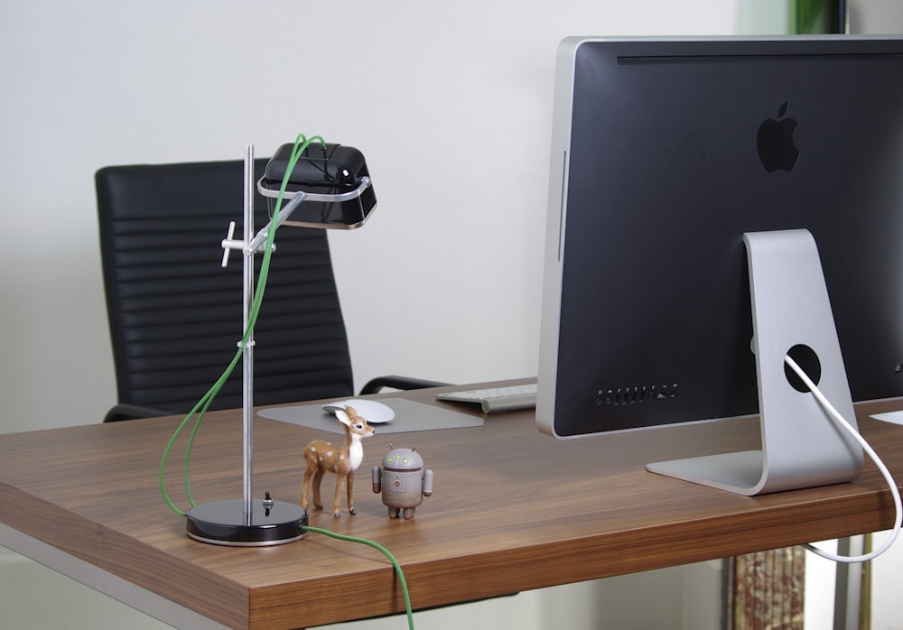 a desk with a computer and a toy horse on it