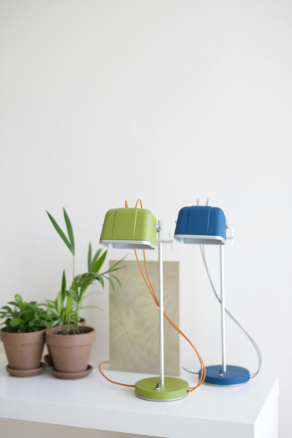 a white table topped with a lamp and a potted plant