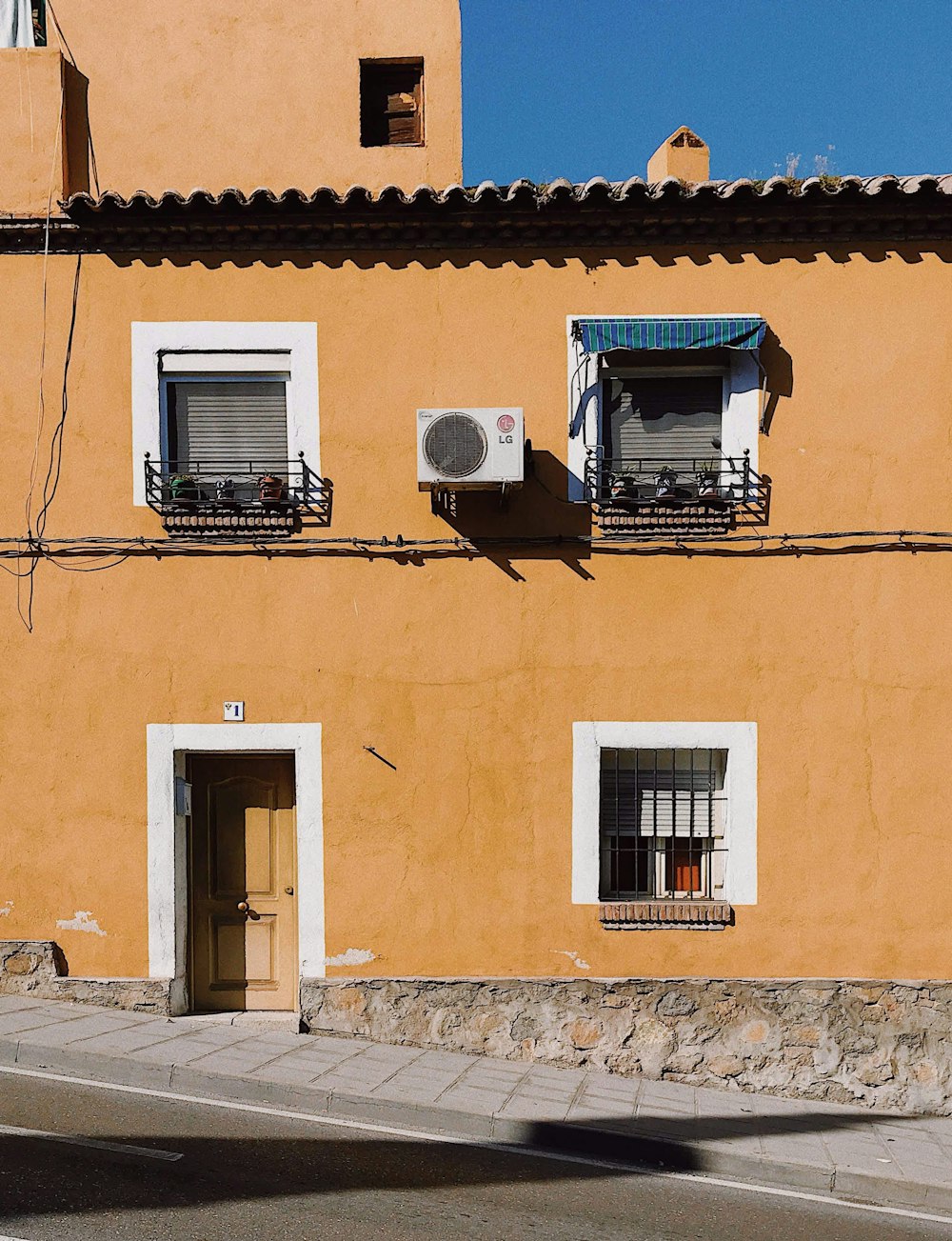 a yellow building with two balconies and two windows