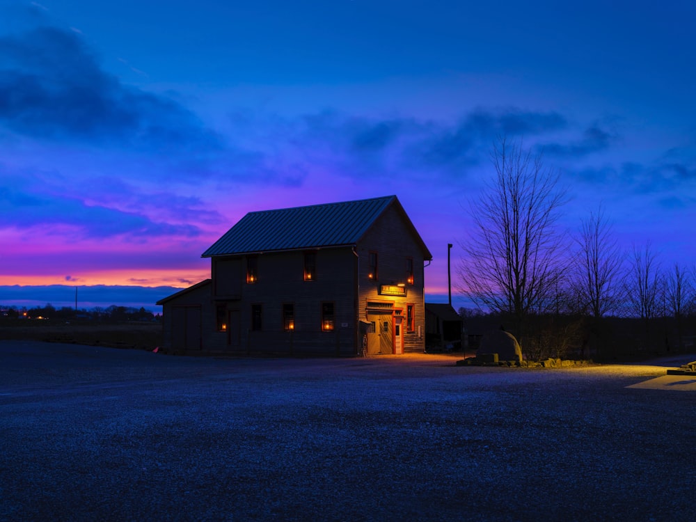 a barn lit up at night with a purple sky