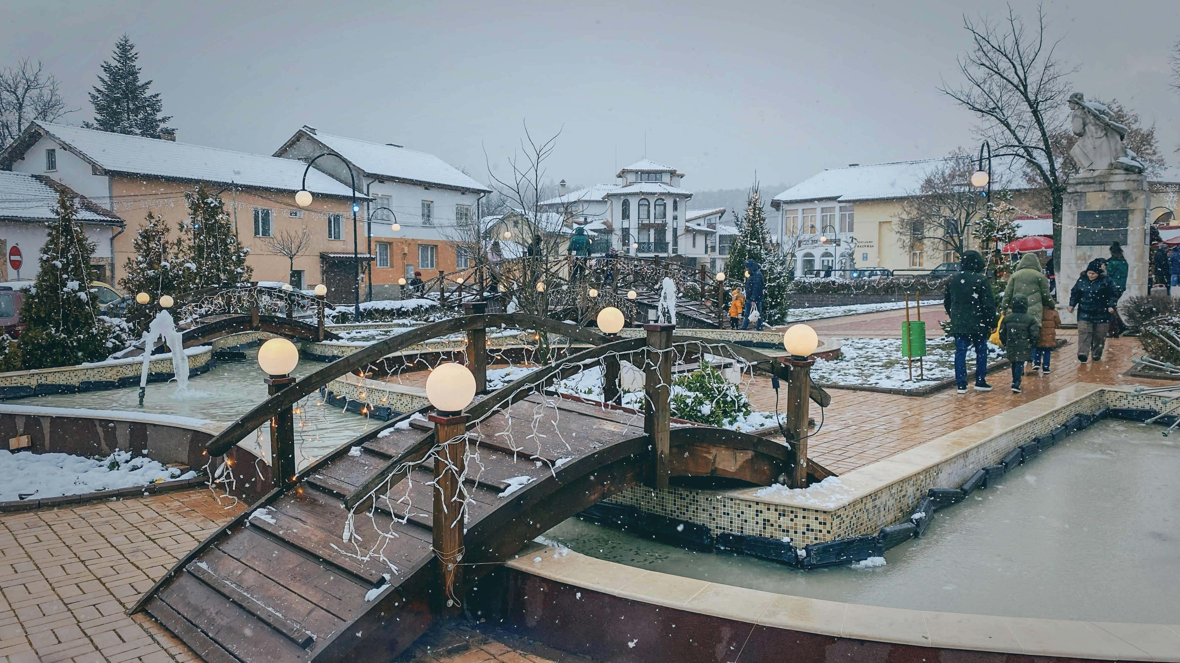 a group of people walking across a snow covered bridge