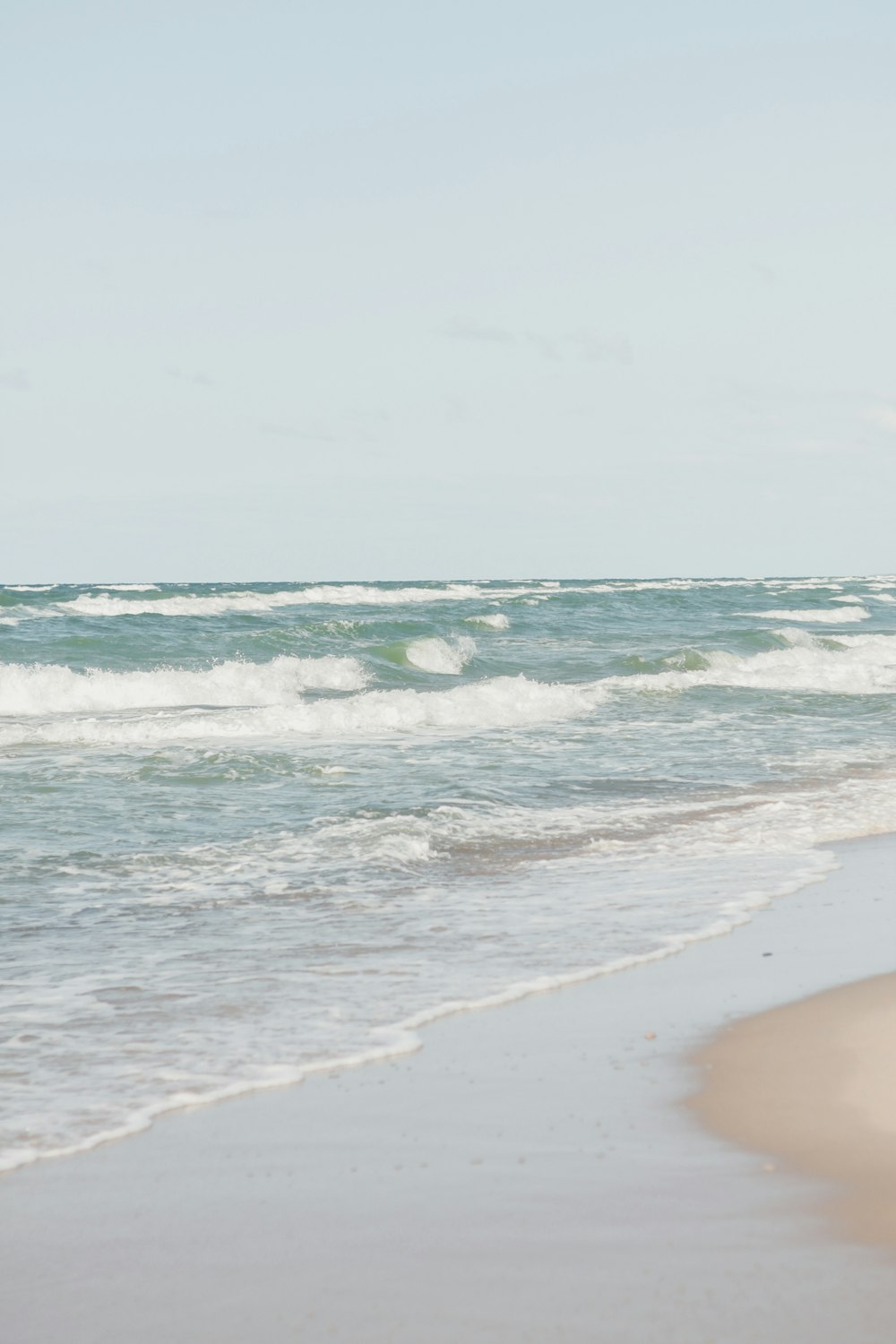 a person walking on the beach with a surfboard