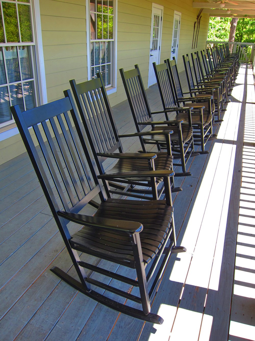 a row of rocking chairs sitting on a porch