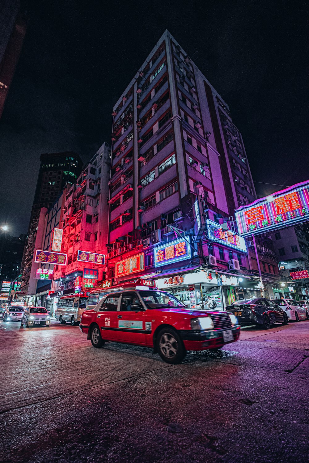 a red taxi cab driving down a street next to tall buildings