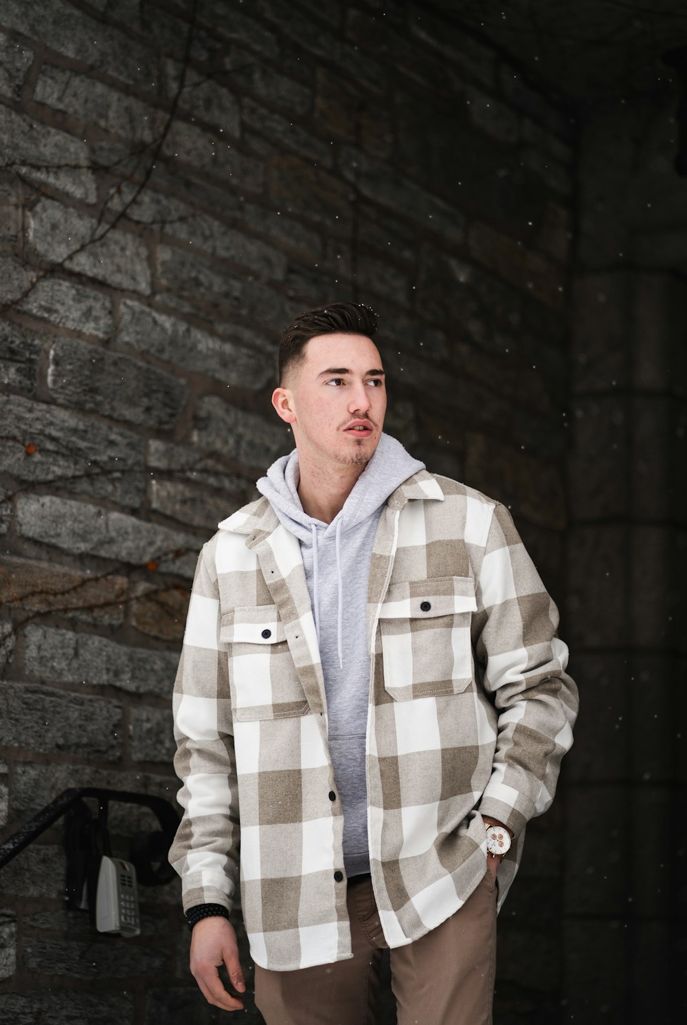 a man standing in front of a brick wall