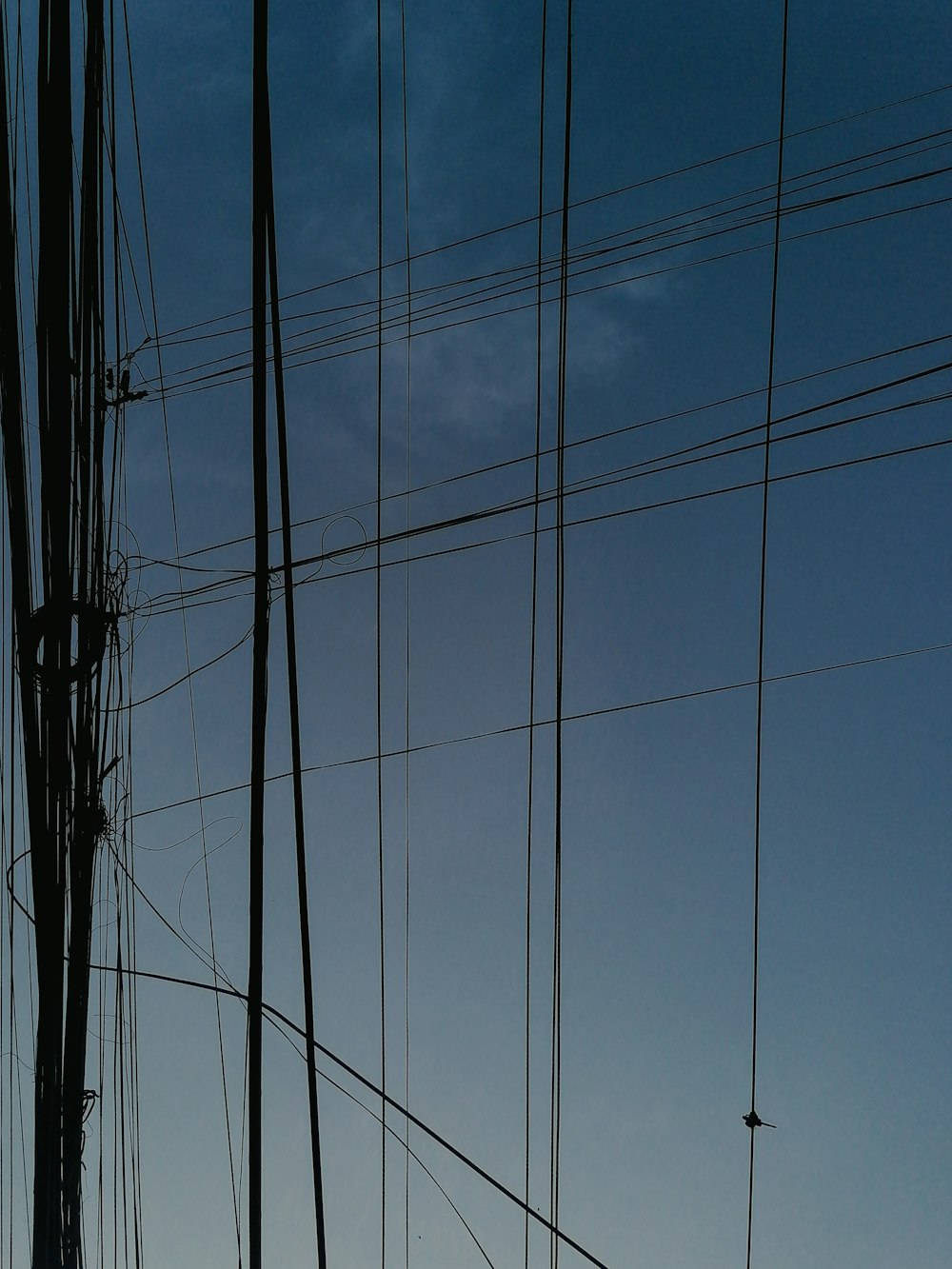 the silhouette of power lines against a blue sky
