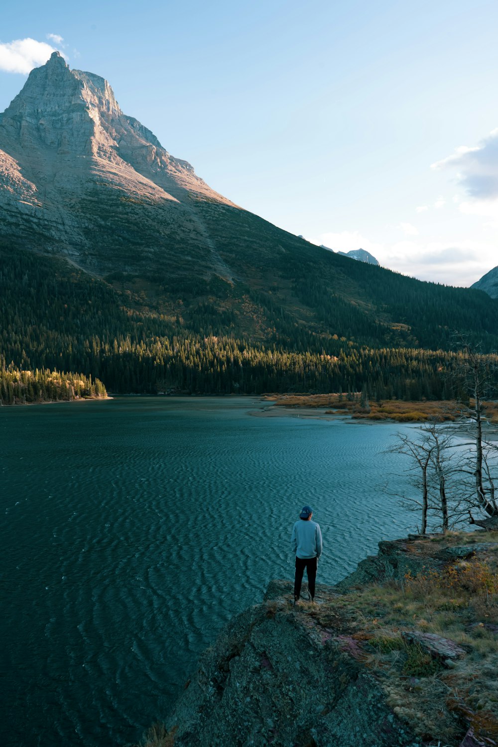 a man standing on the edge of a cliff overlooking a lake