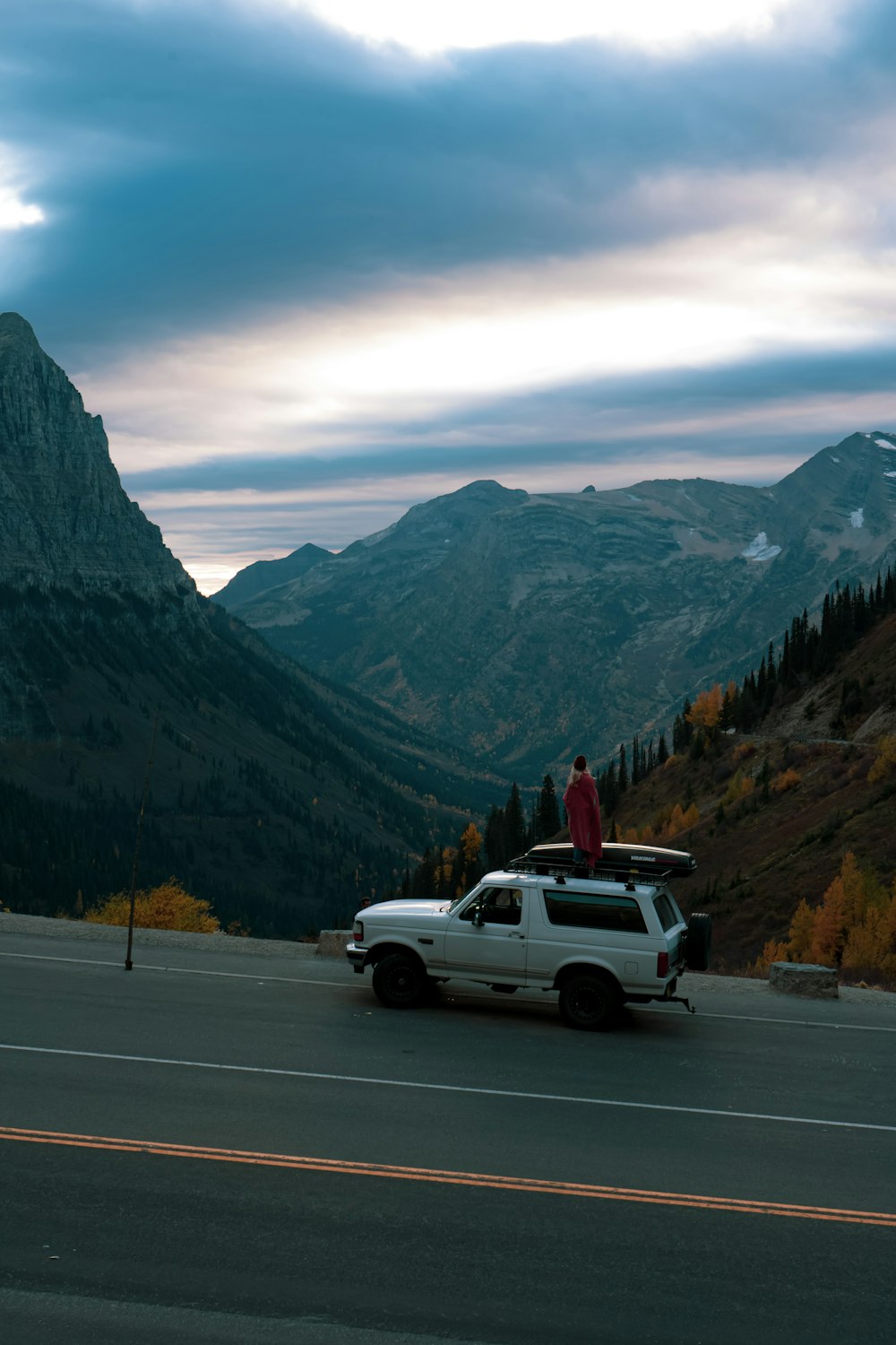 a white truck driving down a road next to a mountain