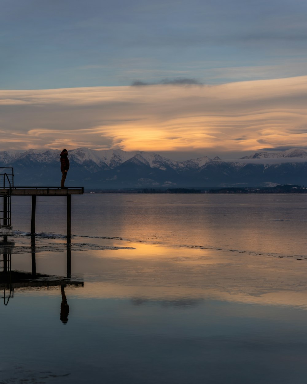 a person standing on a dock at sunset