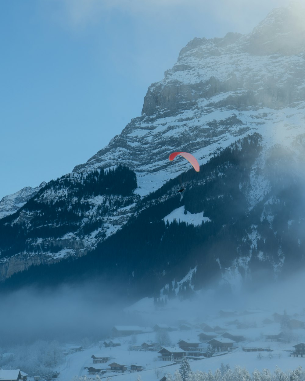 Un parapente vuela sobre una montaña nevada