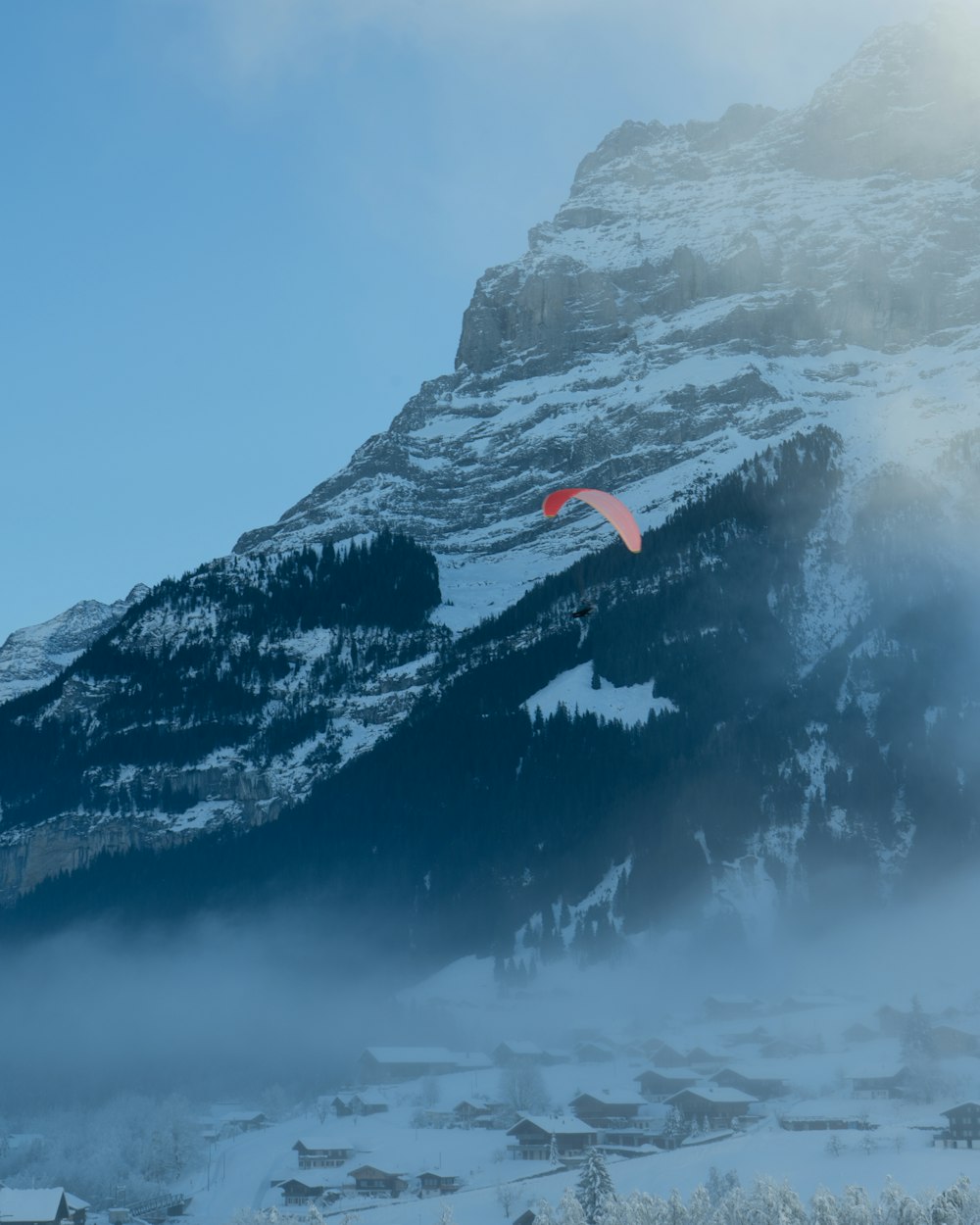 a paraglider is flying over a snowy mountain