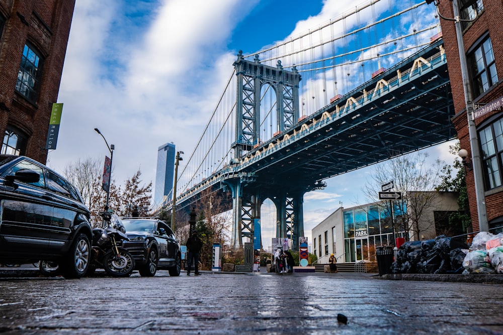 a bridge over a city street with cars parked on the side