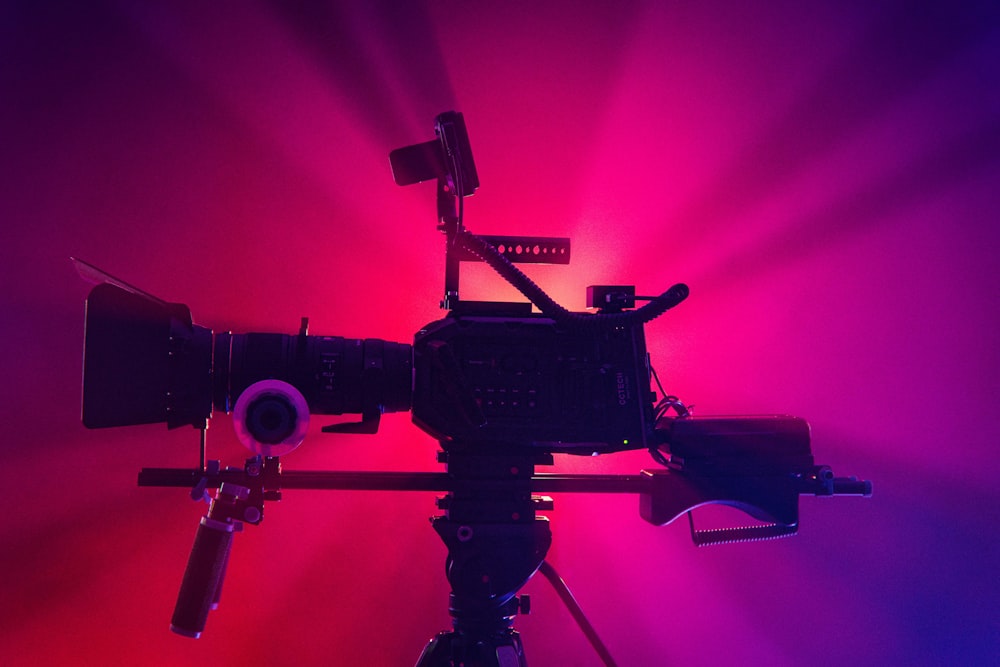 a camera on a tripod in front of a red and purple background