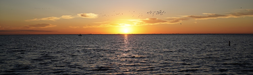 a large body of water with a sunset in the background