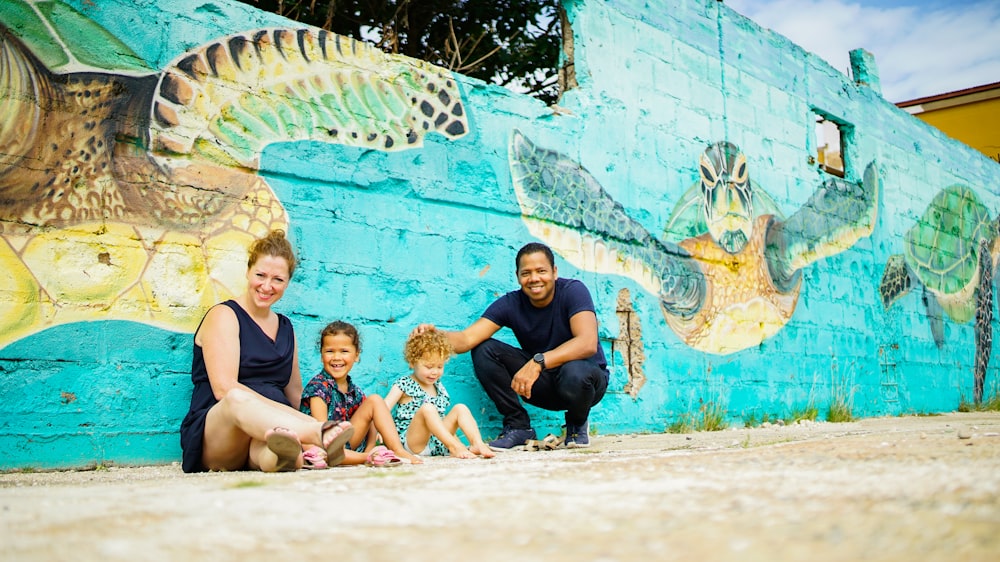 a family poses in front of a painted wall