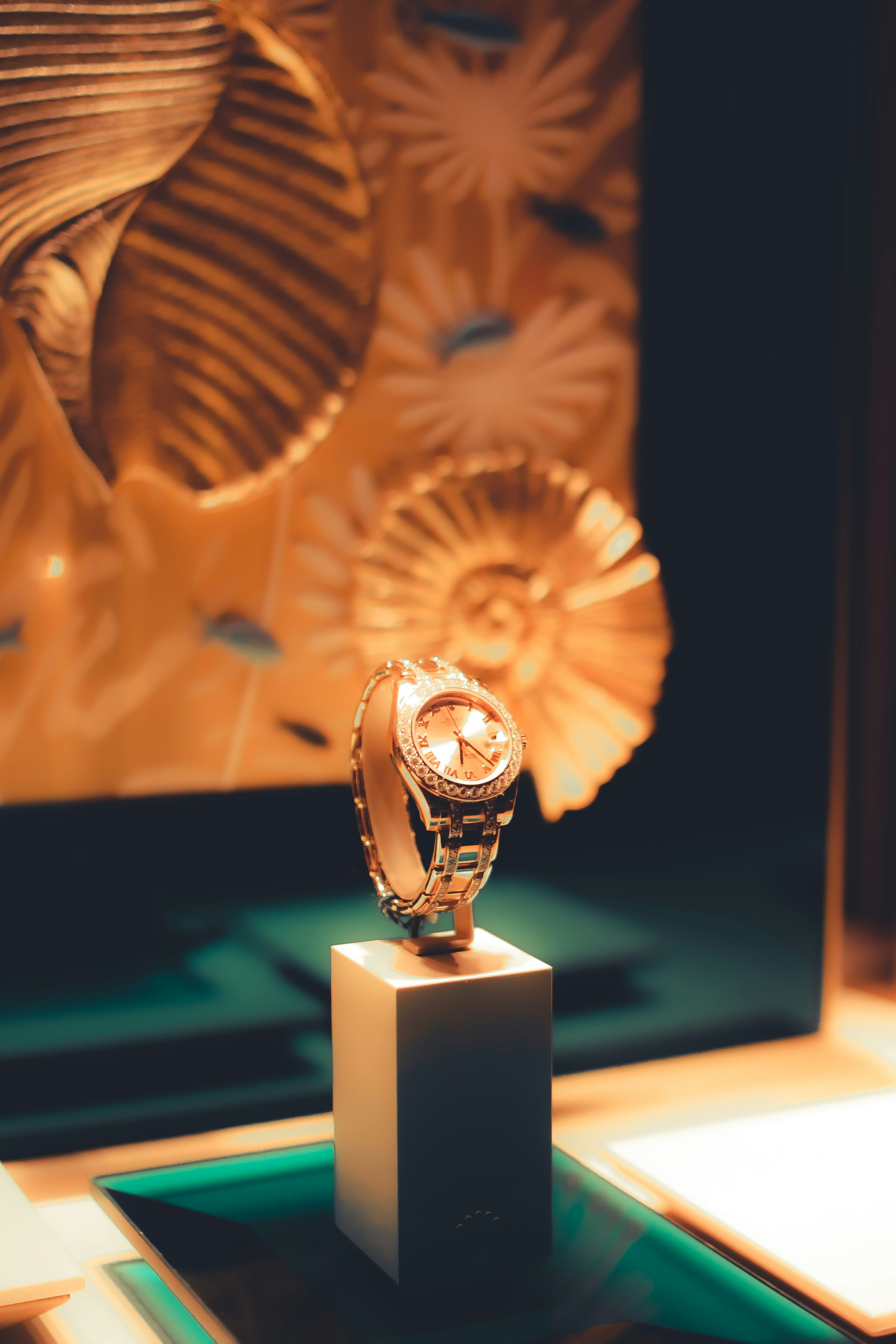 Gold wristwatch with diamond accents rests on a display pedestal.