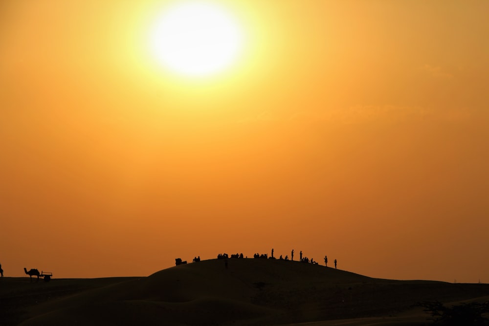 a group of people standing on top of a sandy hill