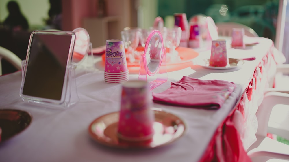 a table set up for a party with pink decorations