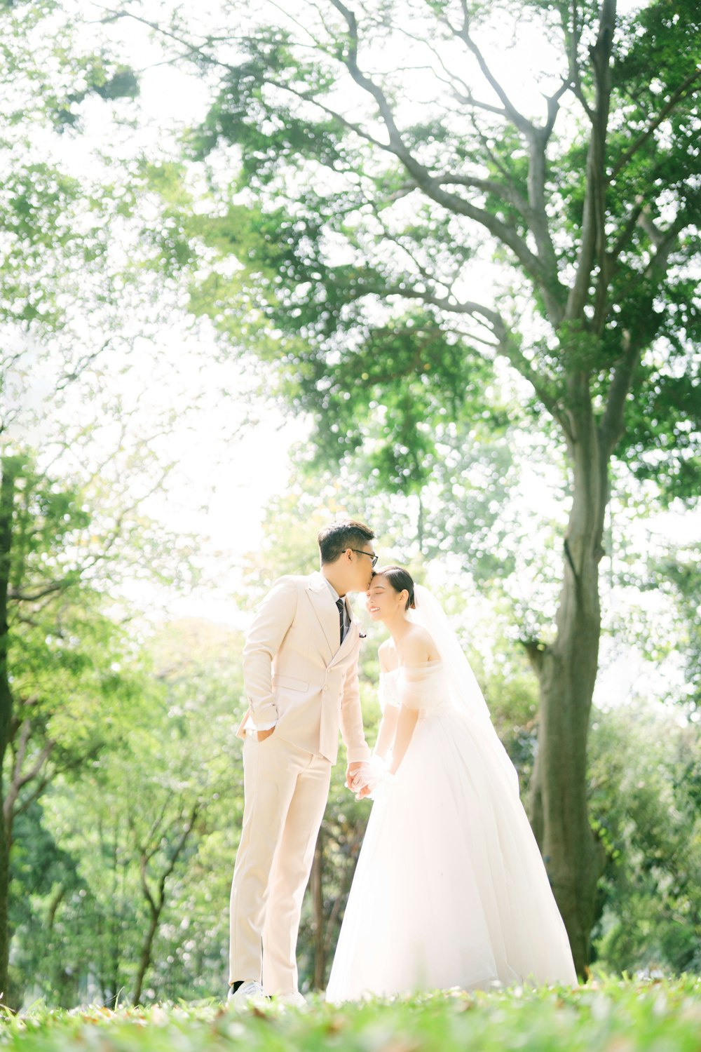 a bride and groom kissing in a park