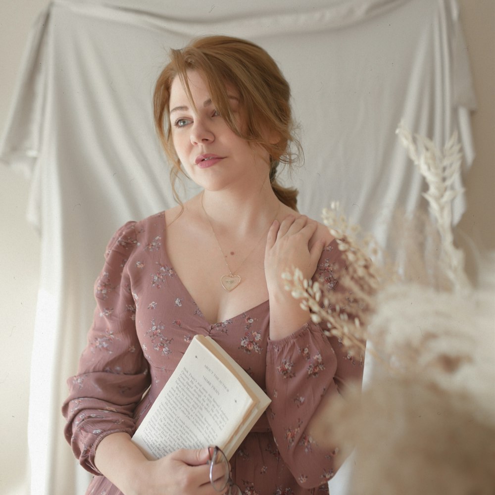 a woman in a pink dress holding a book