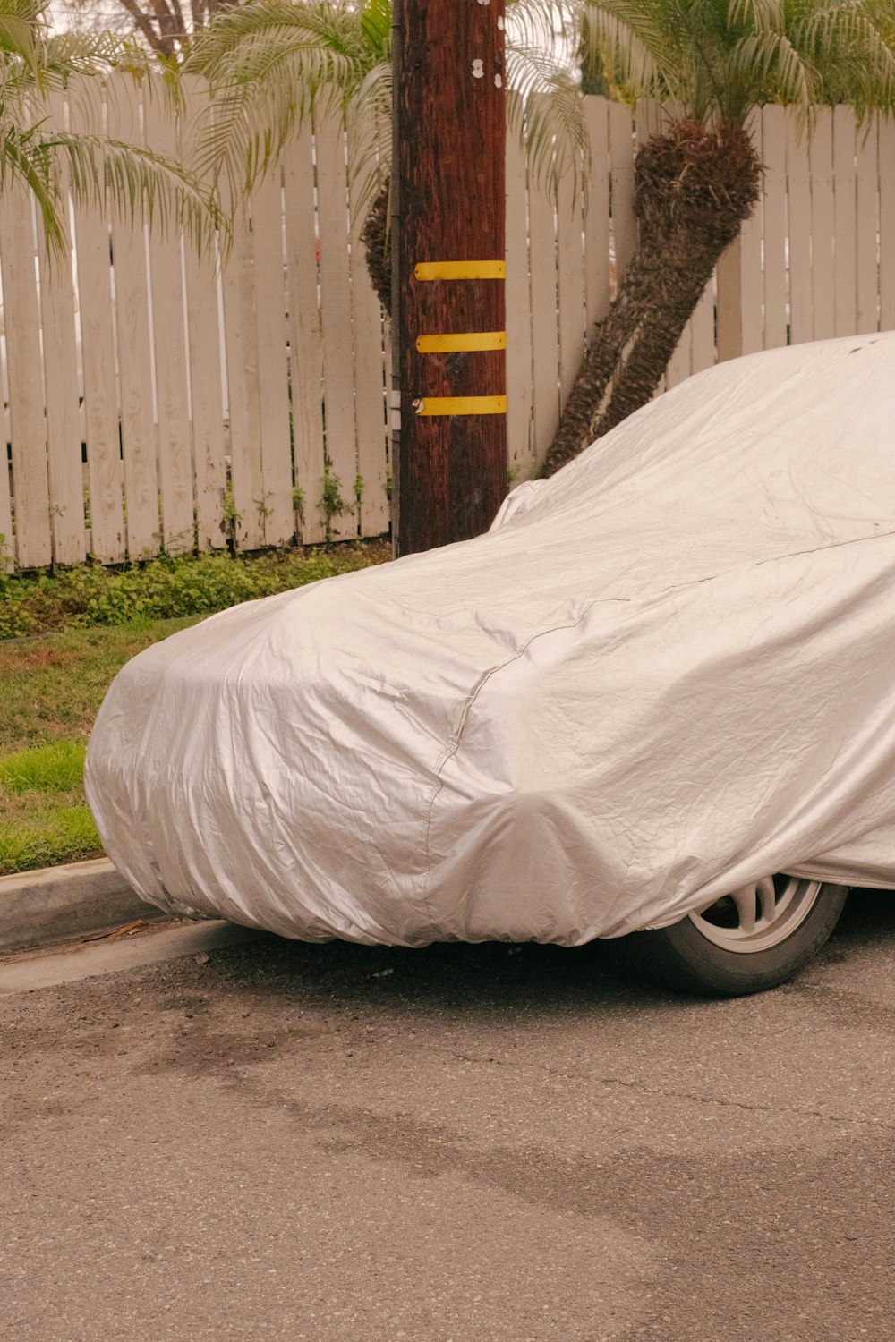 a car covered in a white sheet on the side of the road