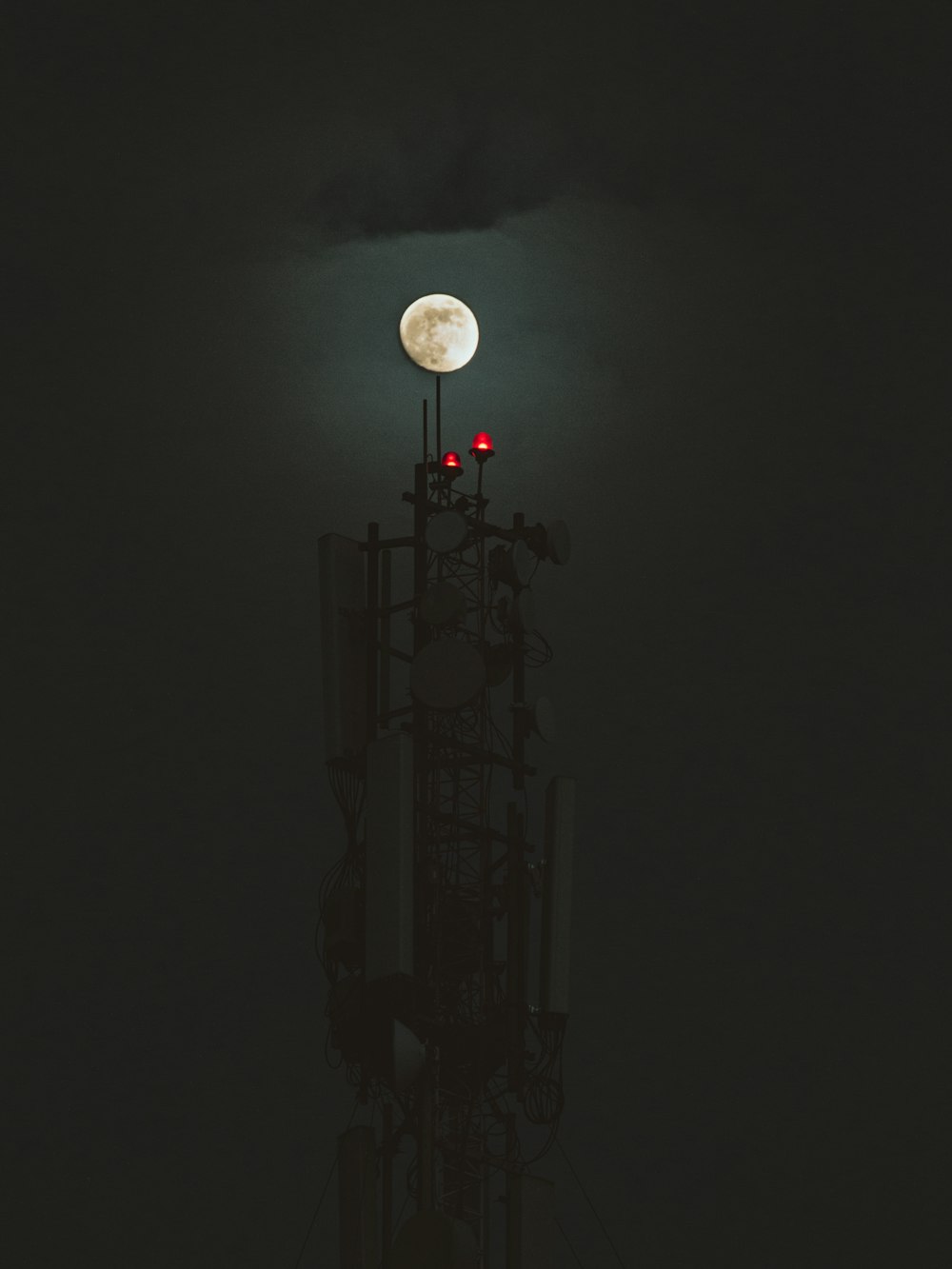 a cell tower with a full moon in the background