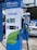 A modern electric vehicle charging station is prominently displayed with the branding 'EV Power' and a capacity of 150kW. The charger features a digital screen and contactless payment options. In the background, an electric car is partially visible under a canopy.