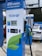 A modern electric vehicle charging station is prominently displayed with the branding 'EV Power' and a capacity of 150kW. The charger features a digital screen and contactless payment options. In the background, an electric car is partially visible under a canopy.