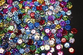 A curated collection of boutique embellishments including beads, sequins, and stones on black satin.